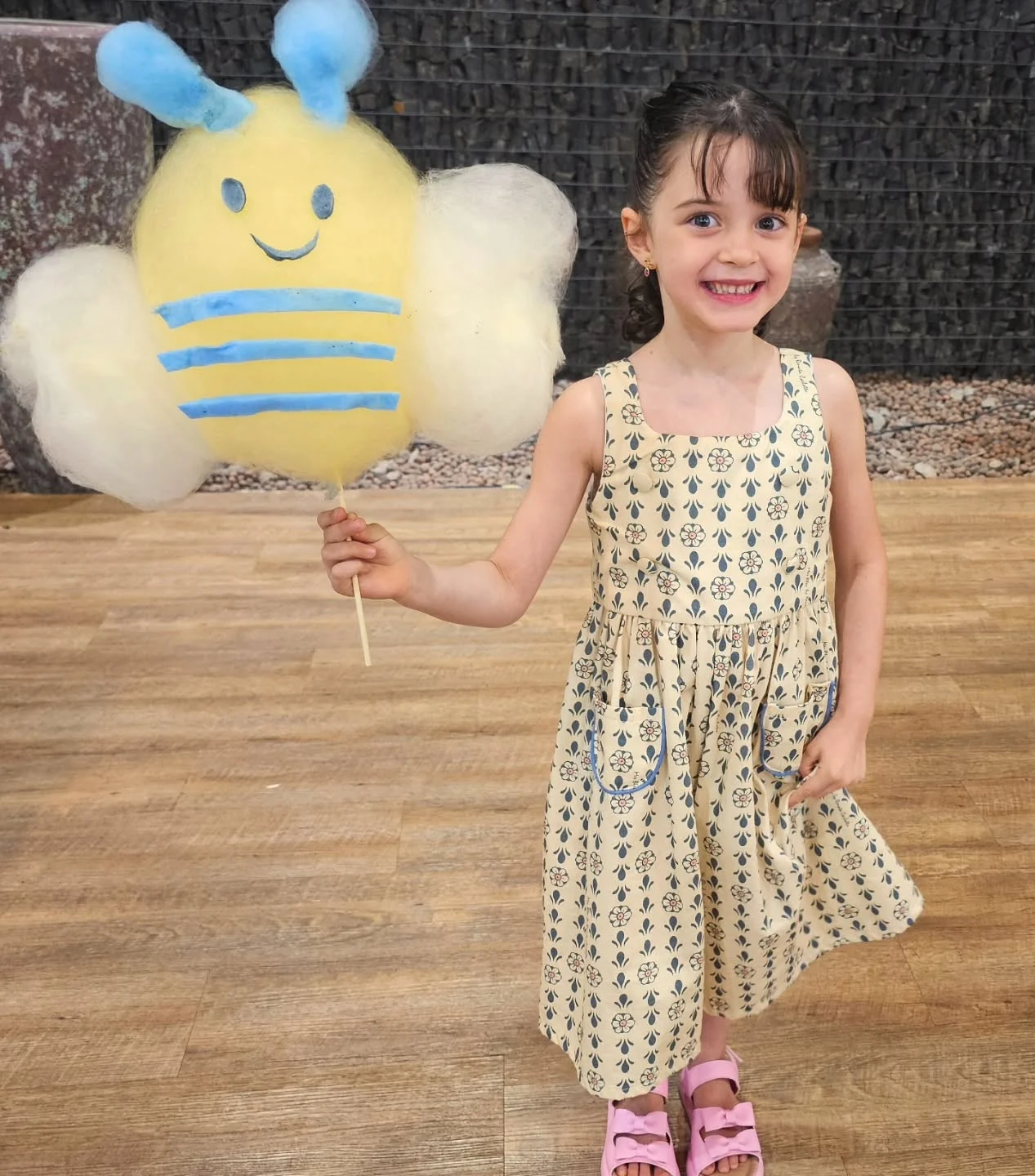 Menina sorrindo com uma abelha de algodão-doce