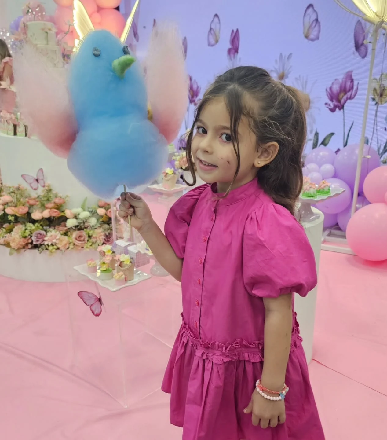 Menina de vestido rosa com um passarinho azul de algodão-doce