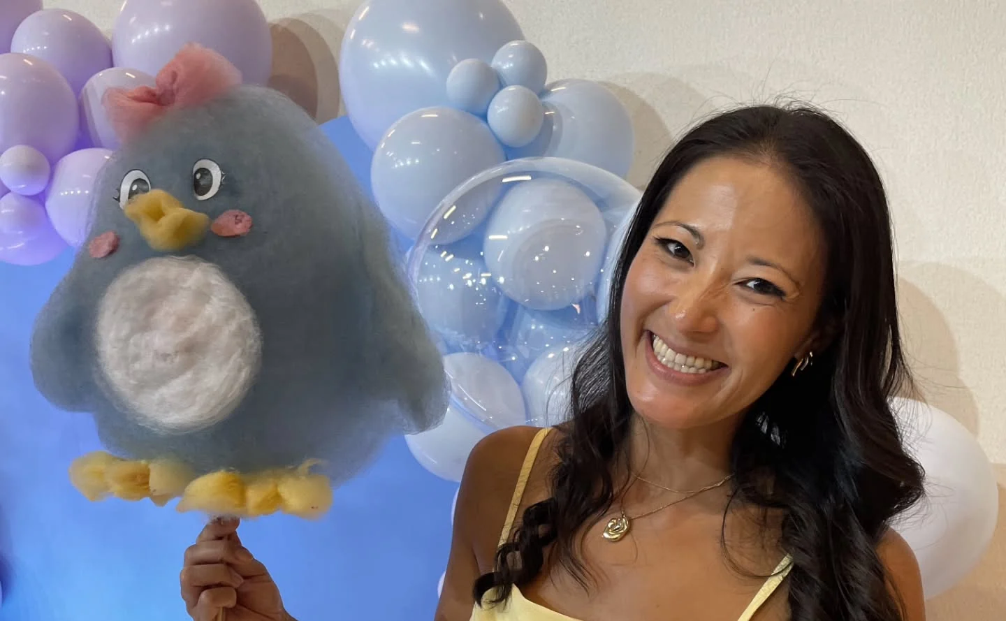 Convidada sorrindo com um pinguim de algodão-doce