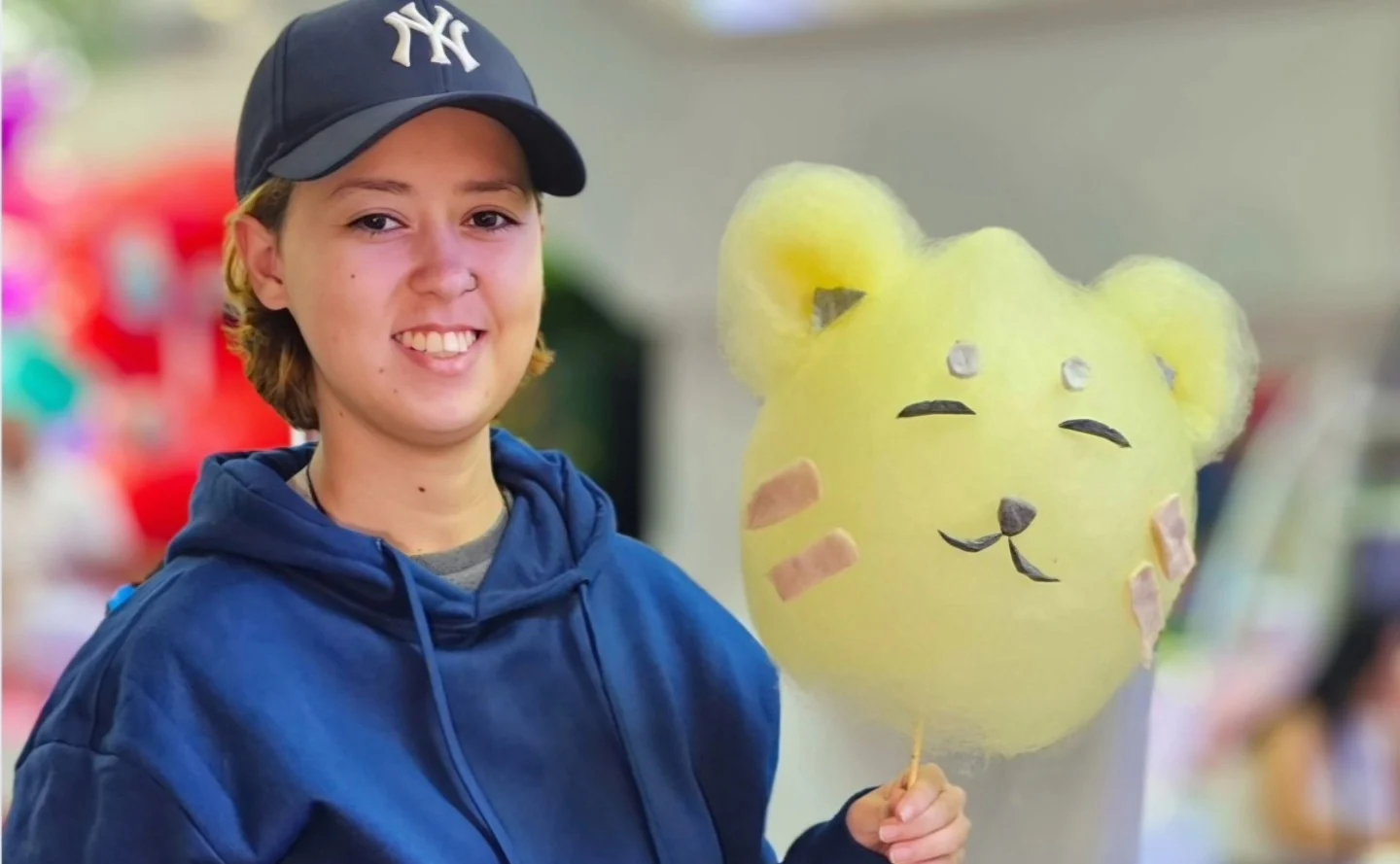 Jovem de boné sorrindo com um gatinho amarelo de algodão-doce